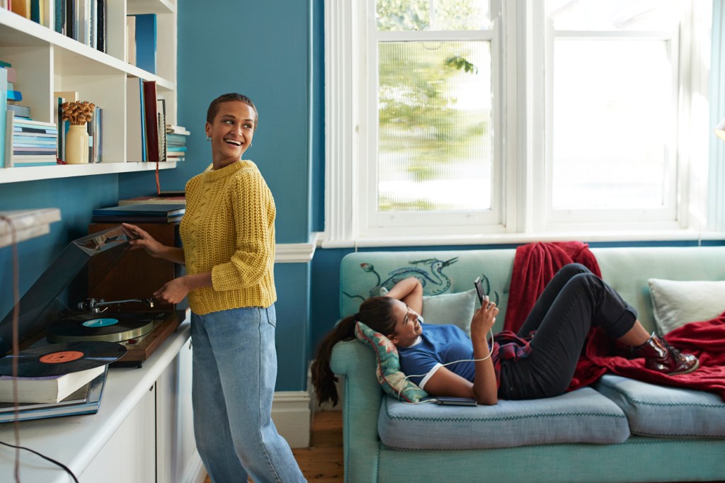 young person standing at record player while housemate