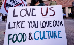 A girl wearing a face mask and holding a sign takes part in a rally "Love Our Communities: Build Collective Power" to raise awareness of anti-Asian violence in March 2021