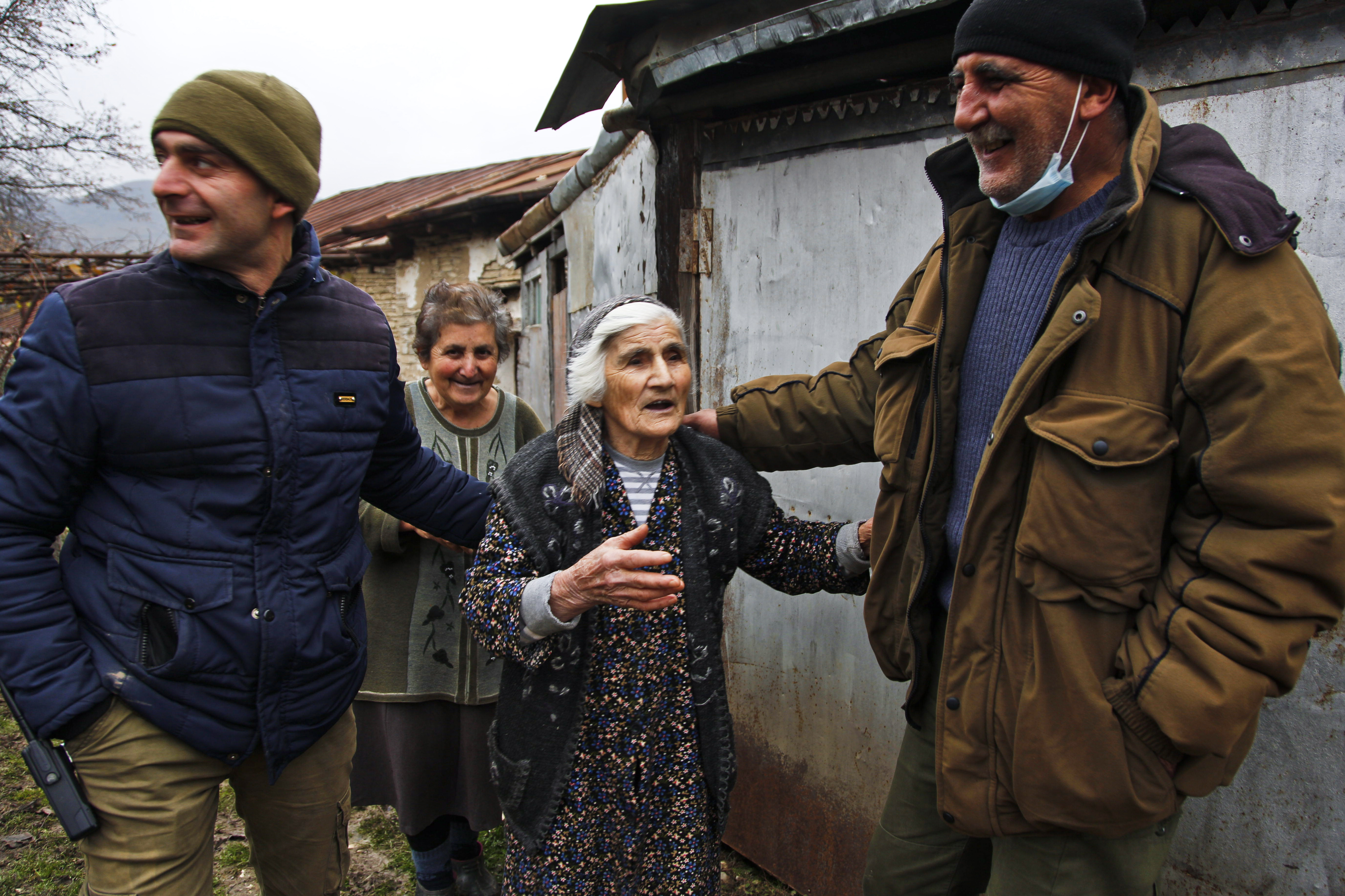 An elderly woman called Mila Babayan and her niece joke with HALO Trust deminers after they cleared her garden of numerous unexploded shells