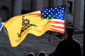 A man holds a flag and listens to a speaker during a rally at South Carolina's Statehouse on Sunday, Jan. 17, 2021, in Columbia, S.C. There was a stepped-up law enforcement presence at the capitol as authorities across the country prepared for potential u