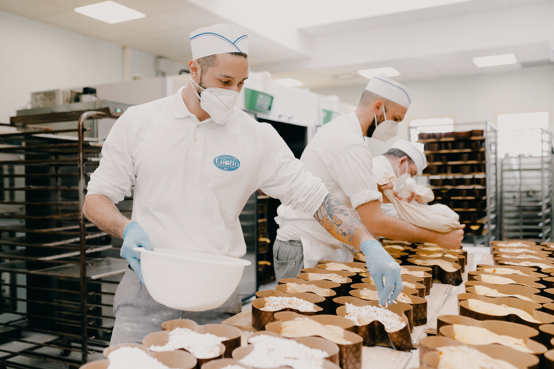 Giotto Bakery – Three men working on a line, two are icing colombe, one sprinkling them.