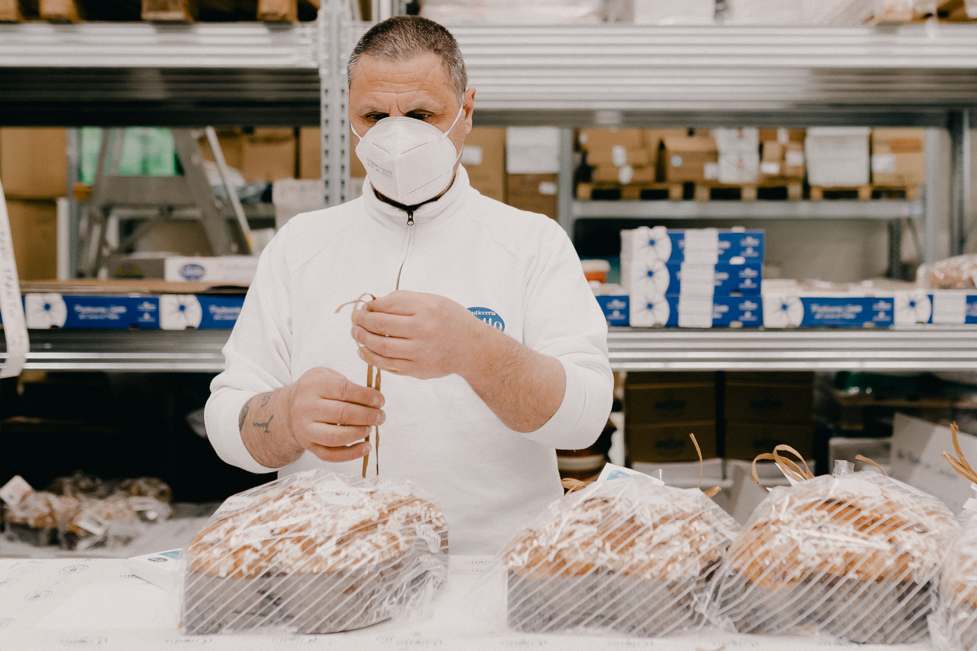 Giotto Bakery – A man tying up the colombe wrapped in a plastic foil with a beige string.