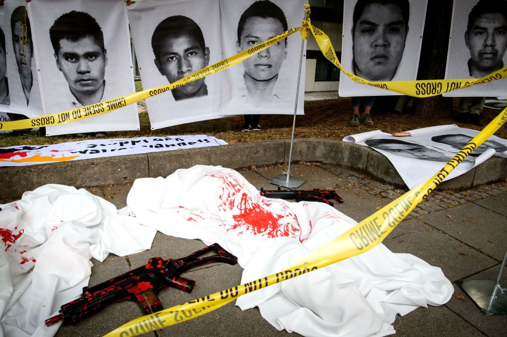 Demonstrators have set up a dummy weapon and portraits of Mexican students who have disappeared and probalby were killed in Mexico in the year 2014, on May 15, 2018 in front of the district court in Stuttgart, southern Germany, where a trial started again