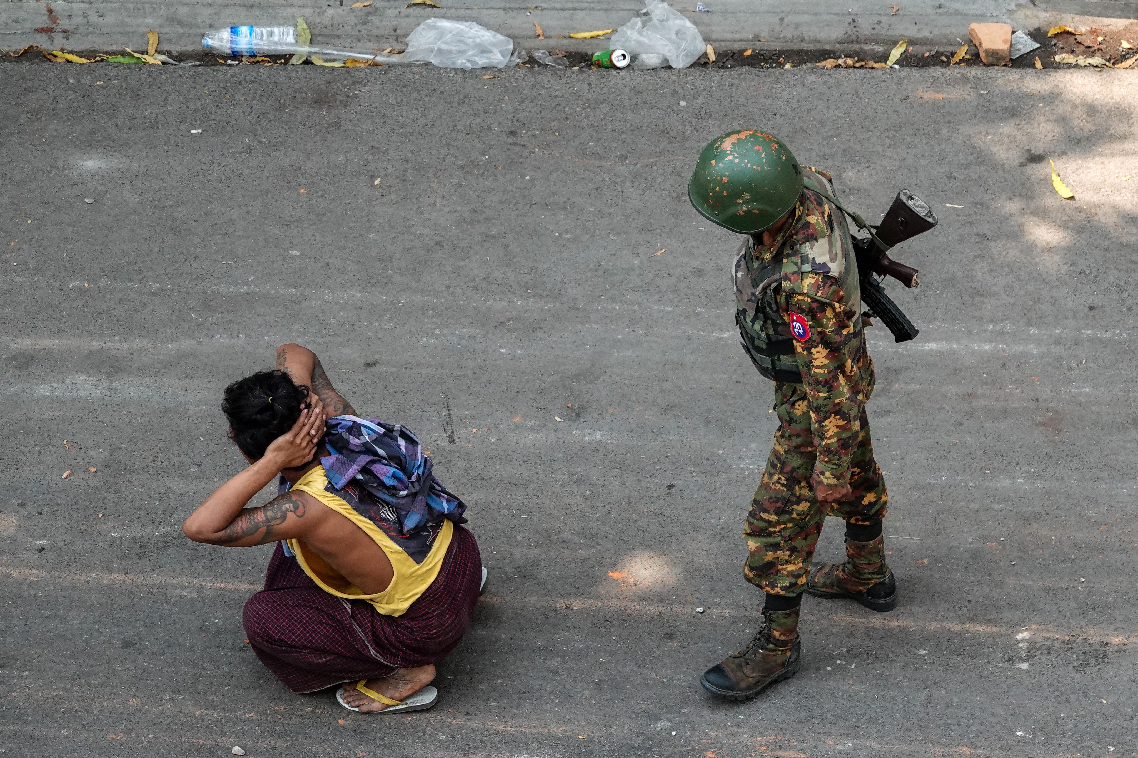 A soldier stands next to a detained man during a demonstration against the military coup in Mandalay. PHOTO: AFP