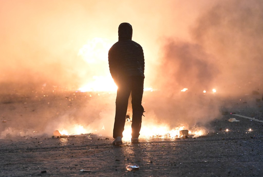 A person looks on as debris burns during clashes at the Springfield Road/ Lanark Way interface on 7th April 2021 in Belfast, Northern Ireland. Photo: Charles McQuillan/Getty Images