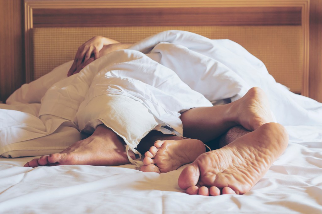 A couple in bed with their limbs intertwined