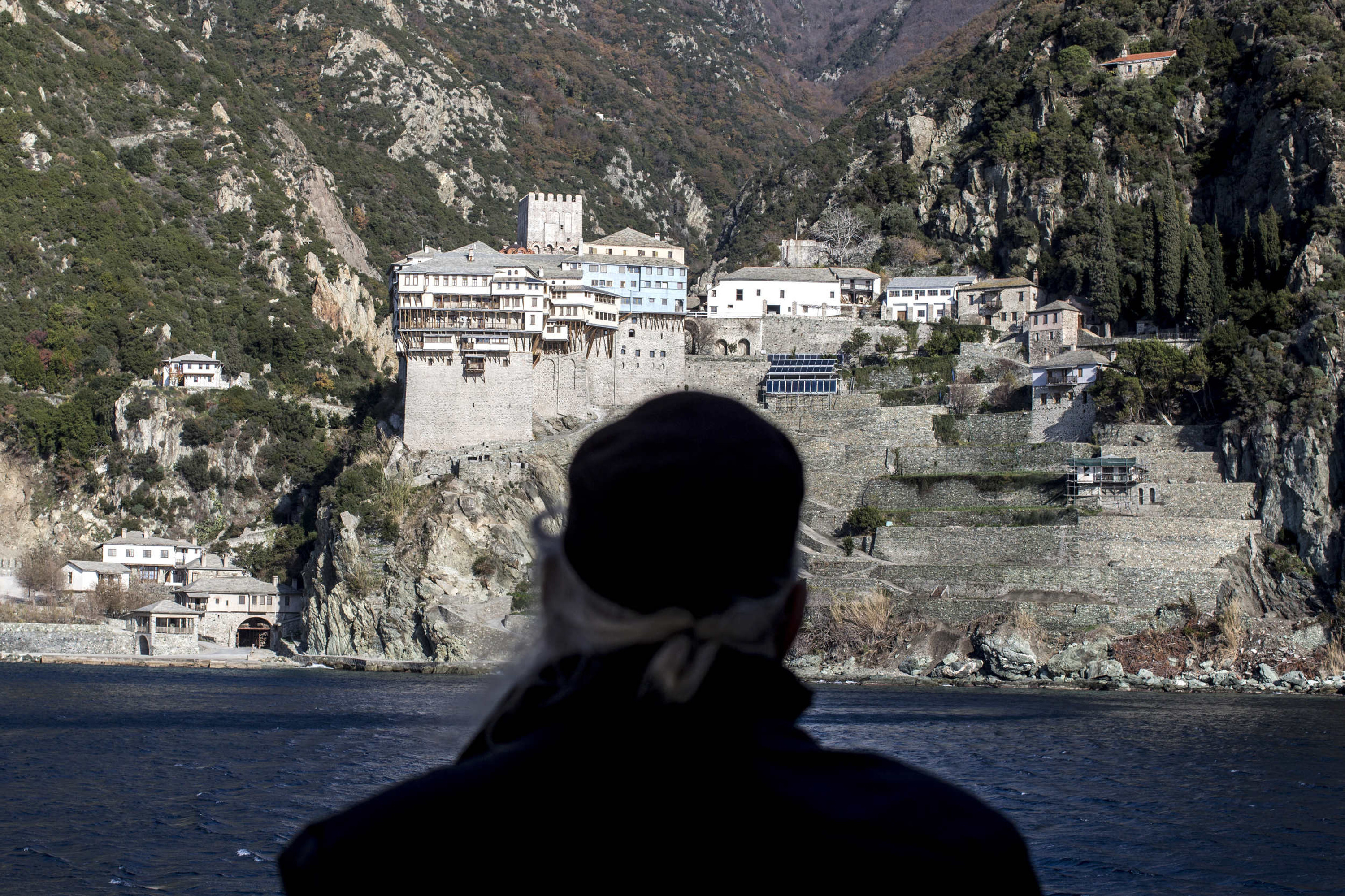 A monk looks toward Dionysiou monastery from a ferry boat before arriving on to the holy mountain of Mt Athos in 2016. Photo: Rick Findler/Getty Images