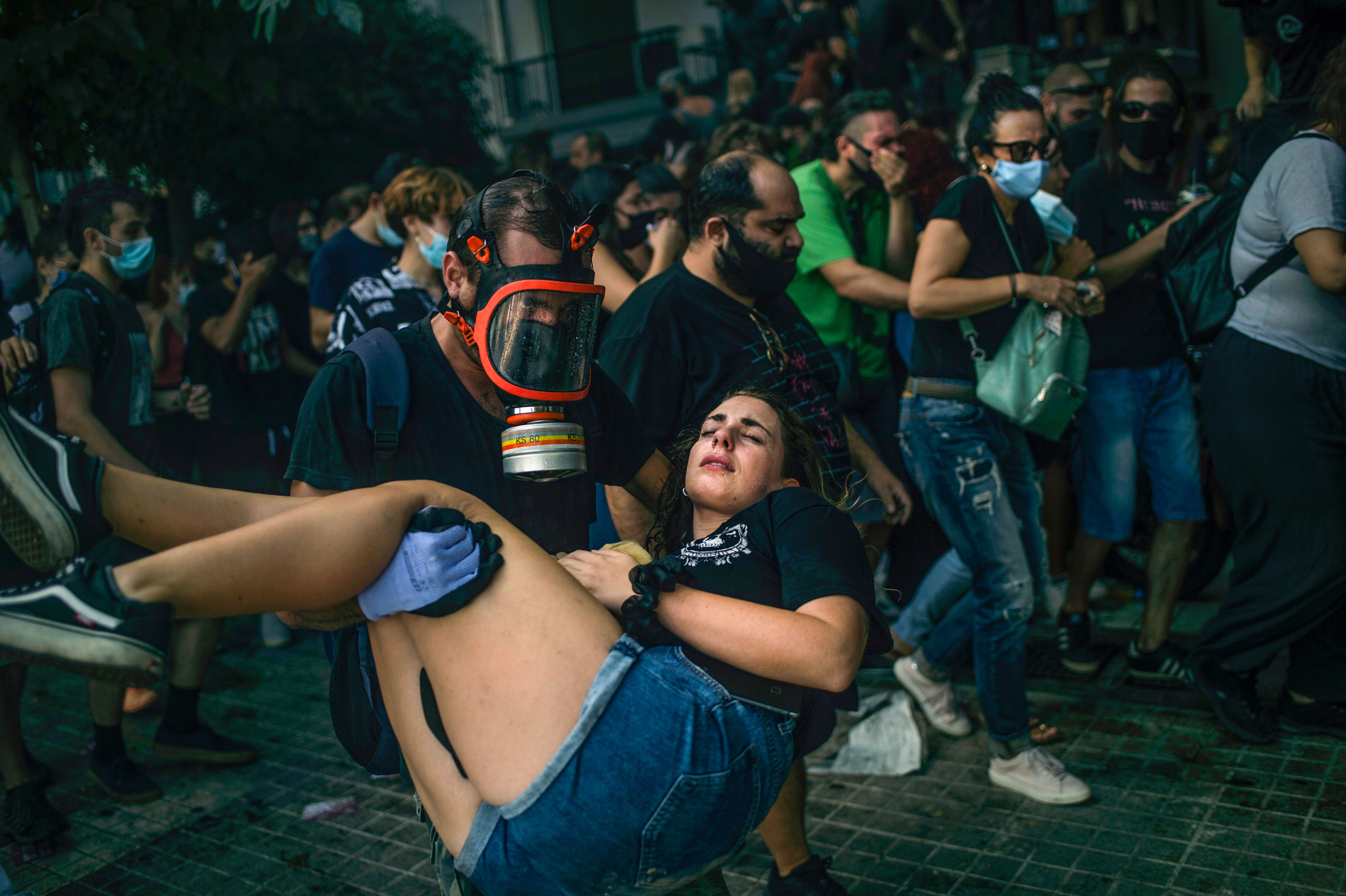 A man helps a fellow protester during scuffles outside court in October 2020 as Golden Dawn's leaders are sentenced. Photo: ANGELOS TZORTZINIS/AFP via Getty Images