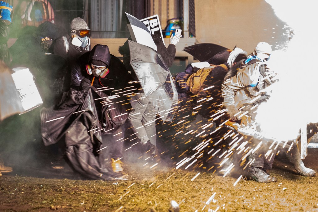 Demonstrators take cover from crowd-dispersal munitions from police outside the Brooklyn Center Police Department while protesting the shooting death of Daunte Wright, late Tuesday, April 13, 2021, in Brooklyn Center, Minn.