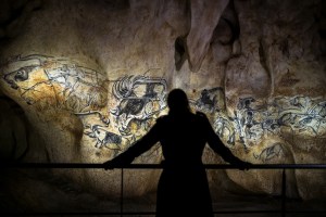 A person looks at part of the full-scale reproduction of frescos found at the cave of Pont-D'Arc also known as the Chauvet cave, on April 8, 2015 in Vallon Pont D'Arc. The frescos were reproduced by French graphic artist and researcher Gilles Tosello, to