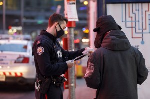 A Toronto police officer speaks with a person in Toronto, Ontario, Canada, on Thursday, Jan. 14, 2021.