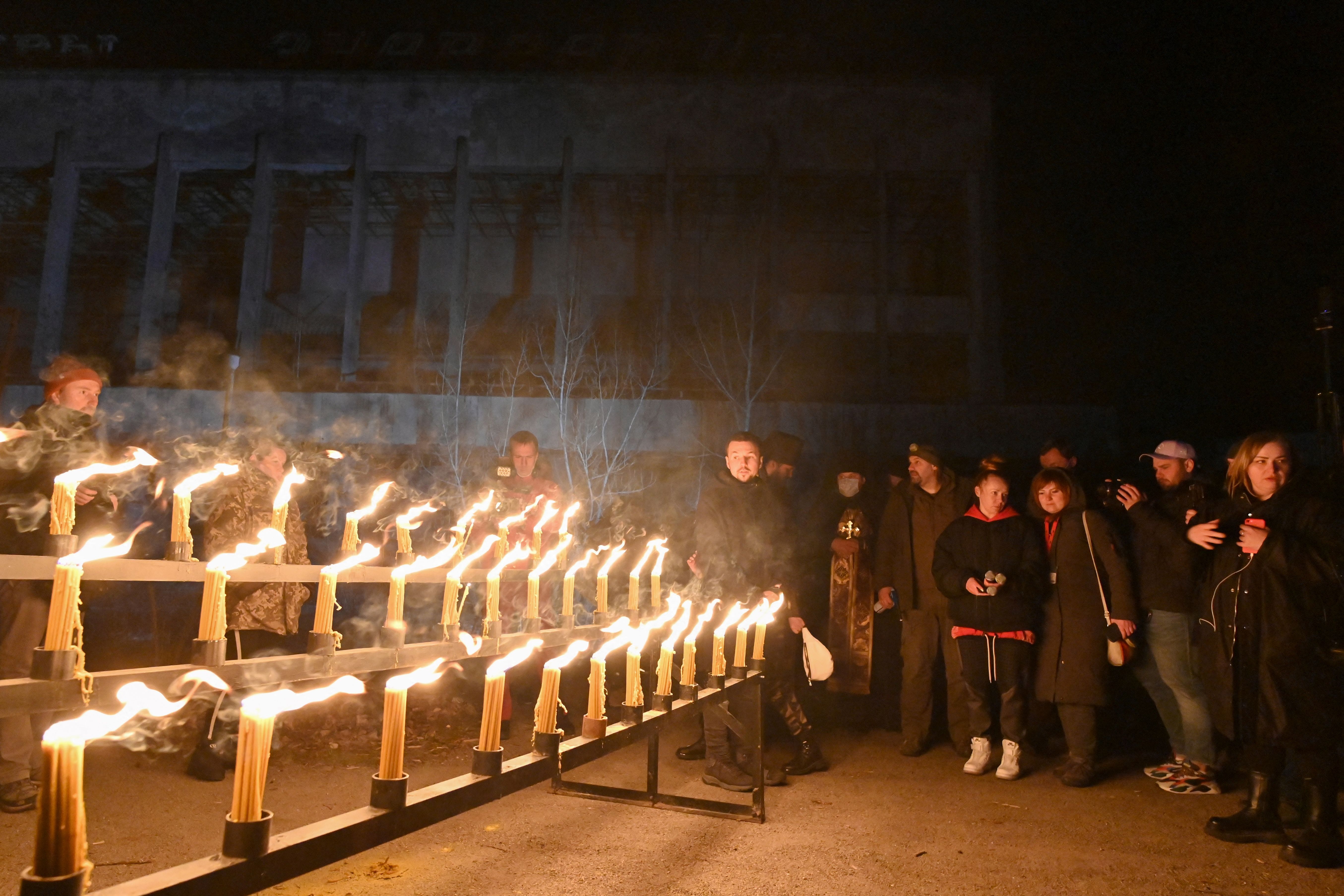 People stand next to lit candles on the central square of the ghost town of Pripyat near the Chernobyl Nuclear Power Plant on early April 26, 2021, to commemorate the 35th anniversary of the Chernobyl nuclear disaster. Photo: Genya SAVILOV / AFP