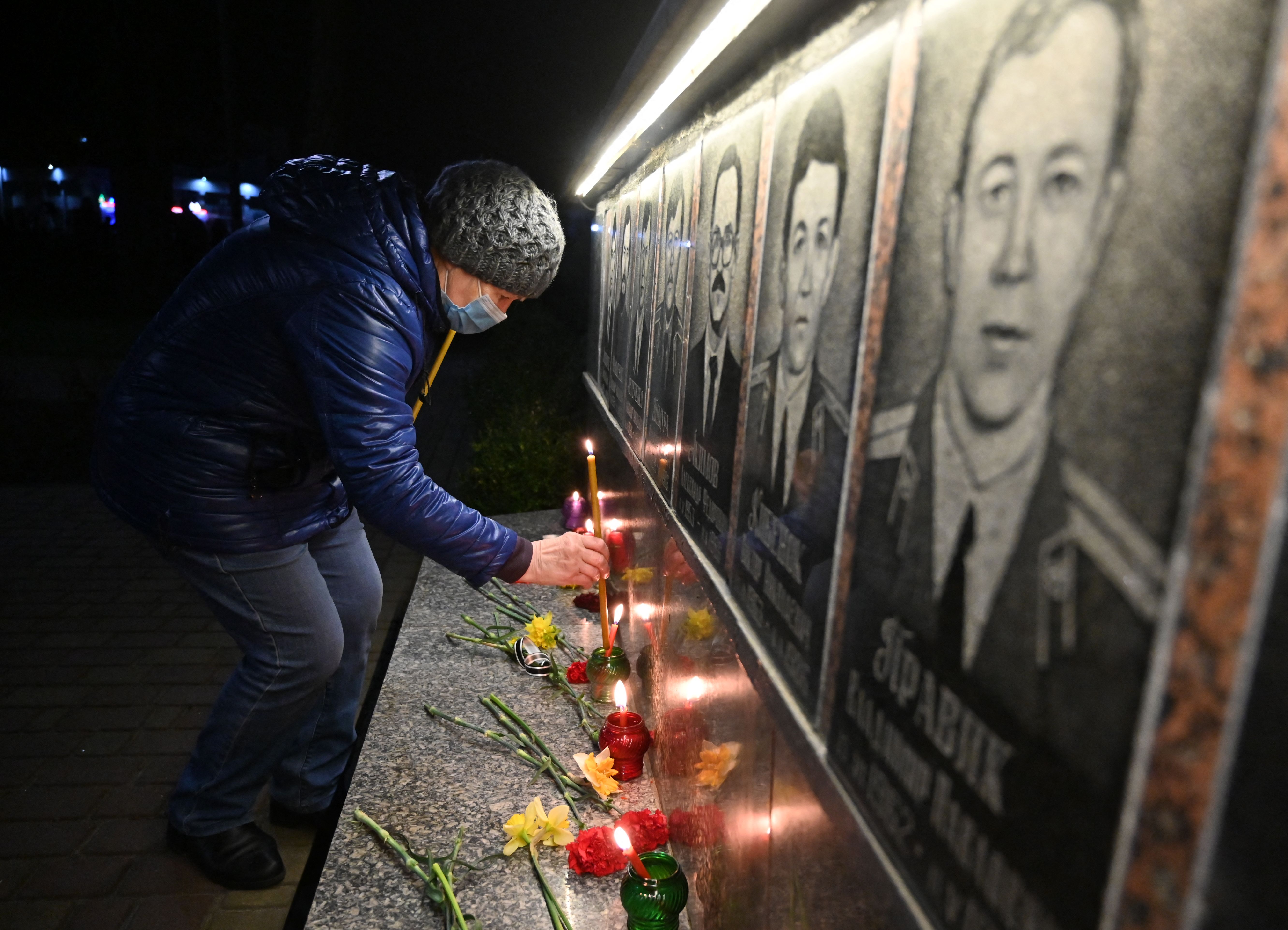 A woman lights a candle at the memorial in Slavutych. Photo: SERGEI SUPINSKY/AFP via Getty Images