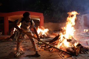 Petugas kremasi membakar tumpukan kayu kremasi