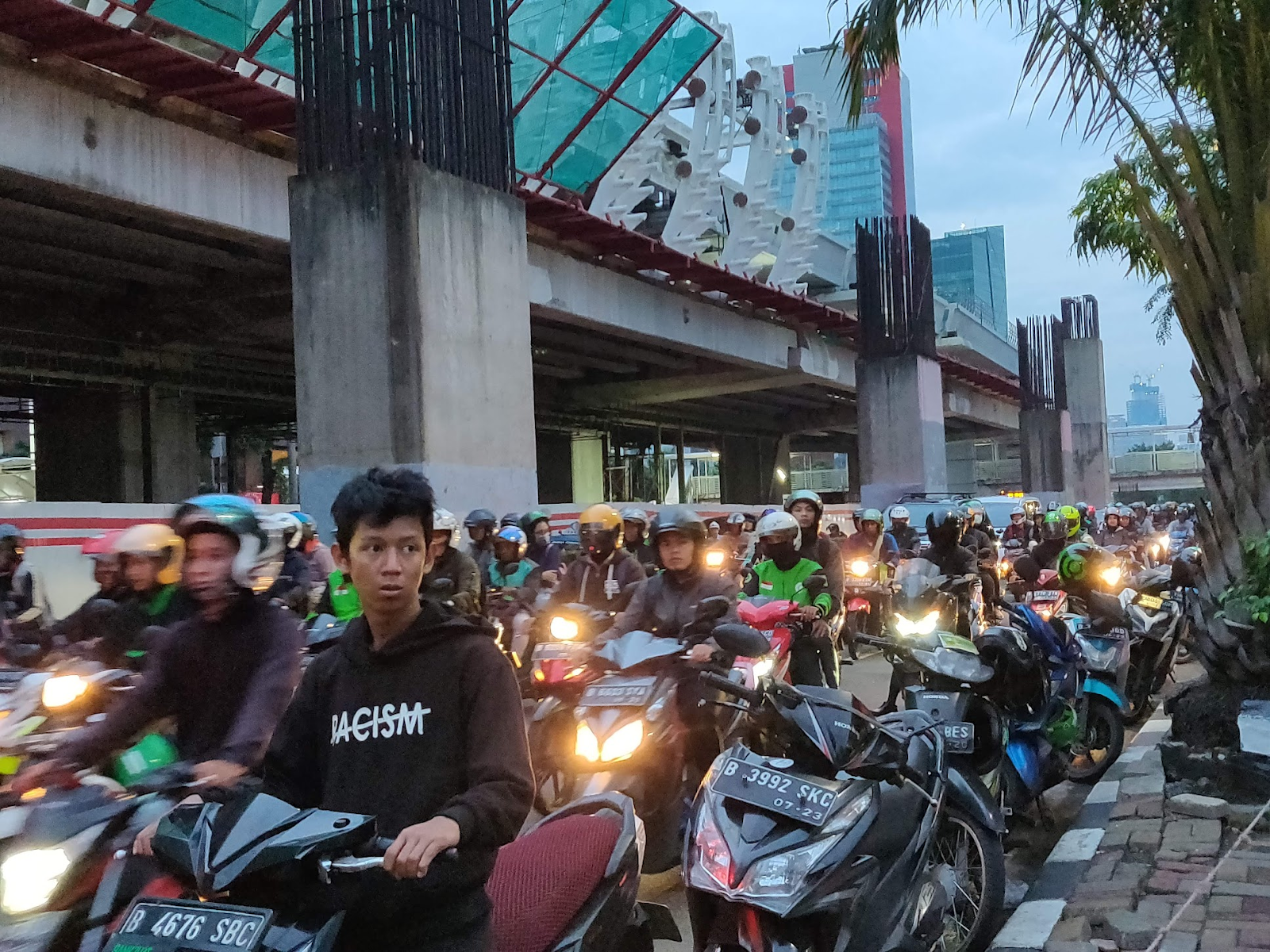 Gojek delivery drivers in green and black jackets wait on their motorbikes on a street in Jakarta