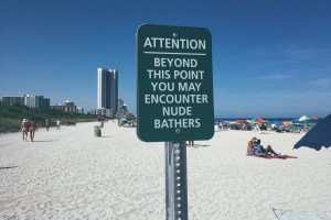 A sign on a beach warning people of nude bathers