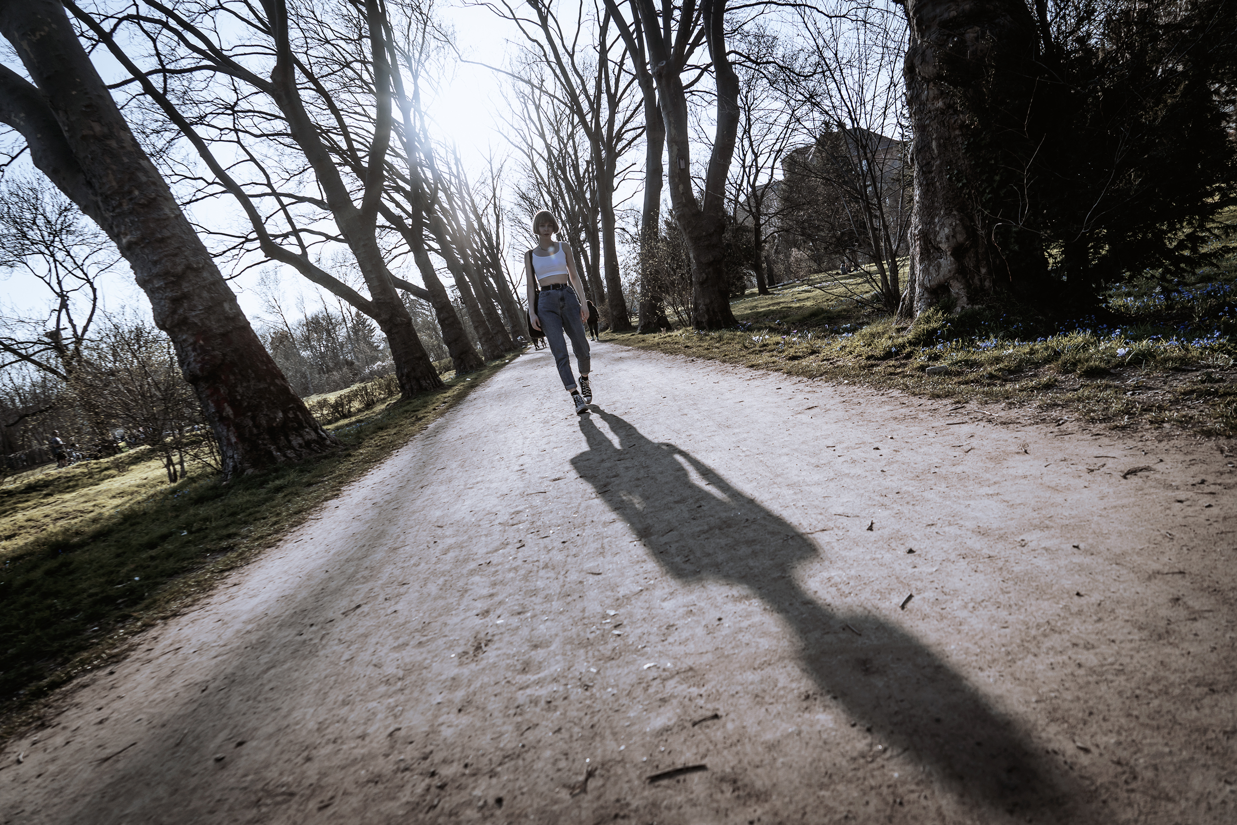 Eine Frau geht mit der Sonne im Rücken einen Weg entlang