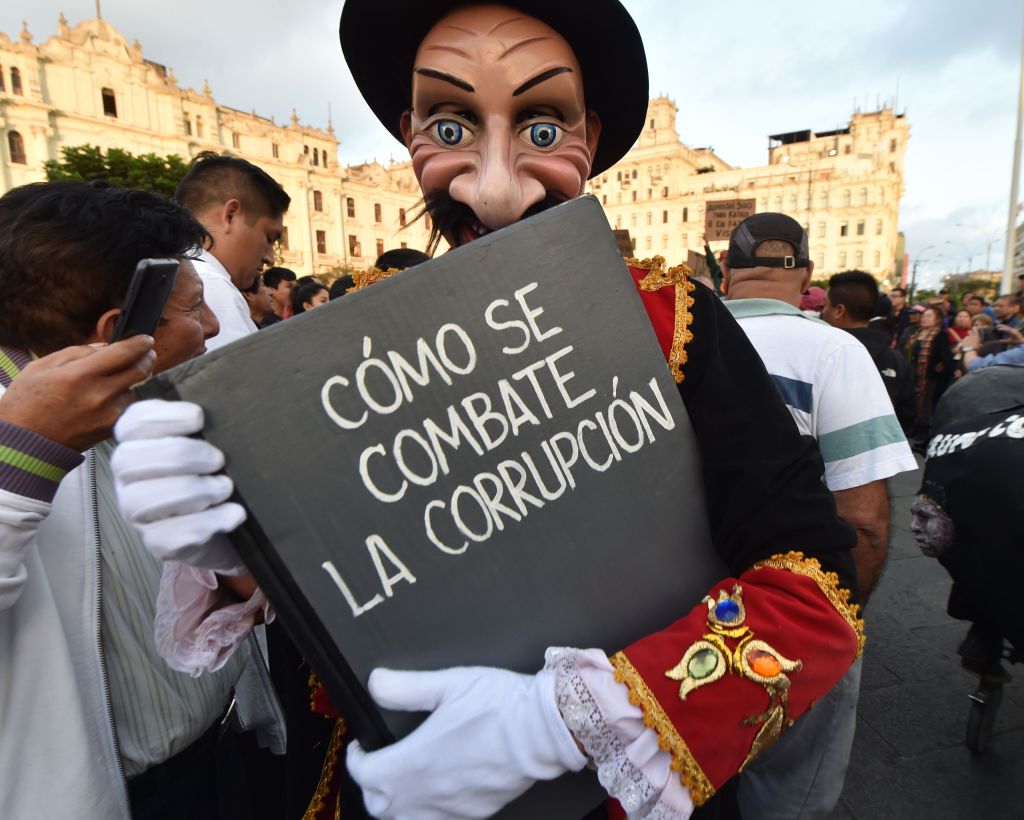 A demonstrator holds a mock book titled "How to combat corruption" during a protest against the Fujimori family and former president Alberto Fujimori in Lima on October 17, 2018.