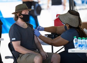 A person getting a Johnson & Johnson vaccine by a health care worker at the one-time pop-up vaccination site located 16th Street beach on the sand on Sunday, May 2, 2021 in Miami Beach. (David Santiago/Miami Herald via AP)