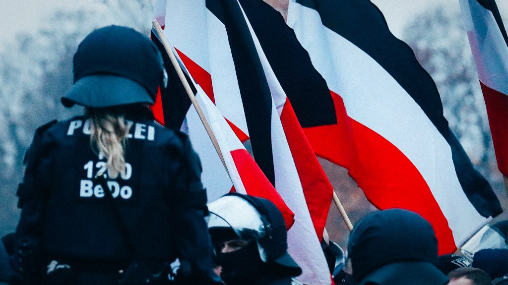 Eine Polizistin steht vor einer Reichsflagge