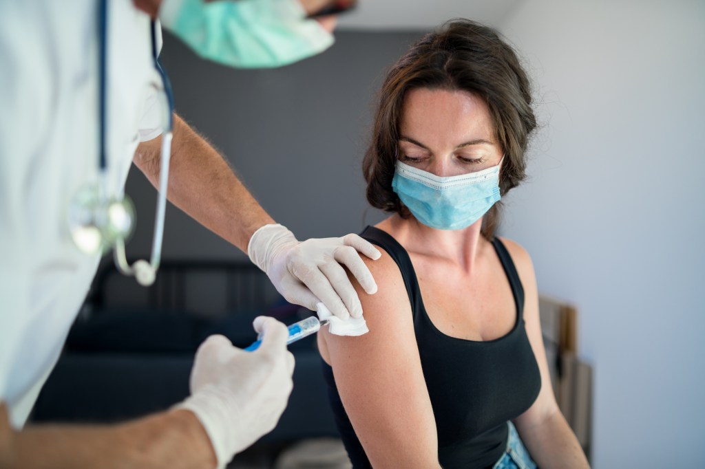 Woman with face mask getting vaccinated, coronavirus concept. - stock photo