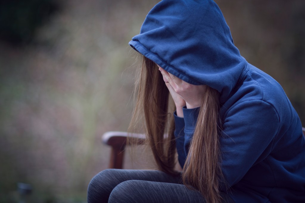 A woman in a hooded top, with her head in her hands. (Stock photo, Getty Images)