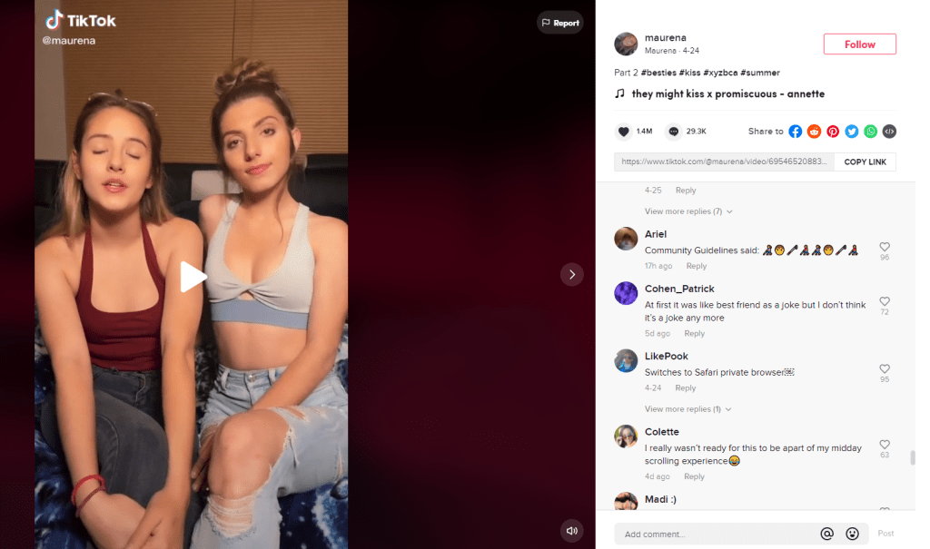 A screenshot of a TikTok featuring two women on a bed. The comments ask if the user had been in violation of the community guidelines.