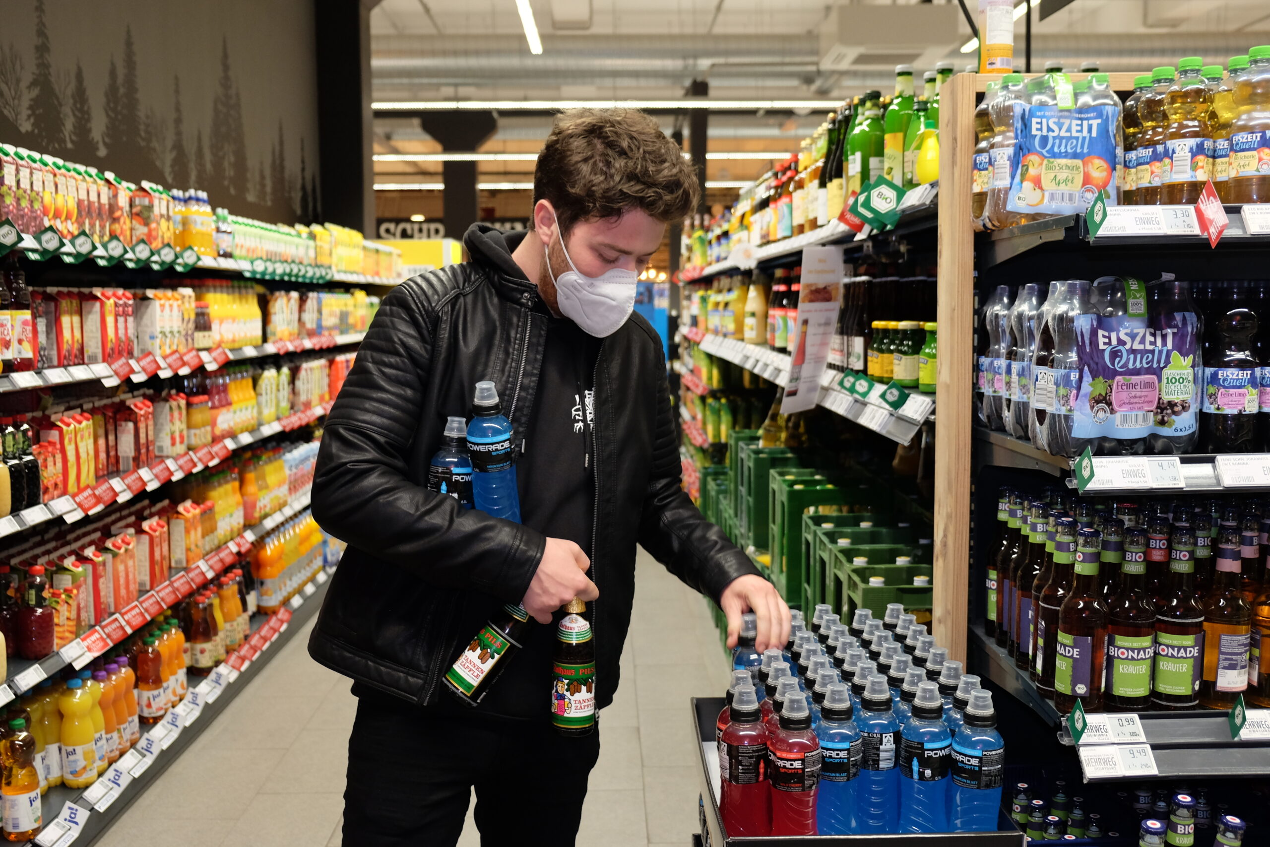 Junger Mann kauft Bier und Powerade im Supermarkt