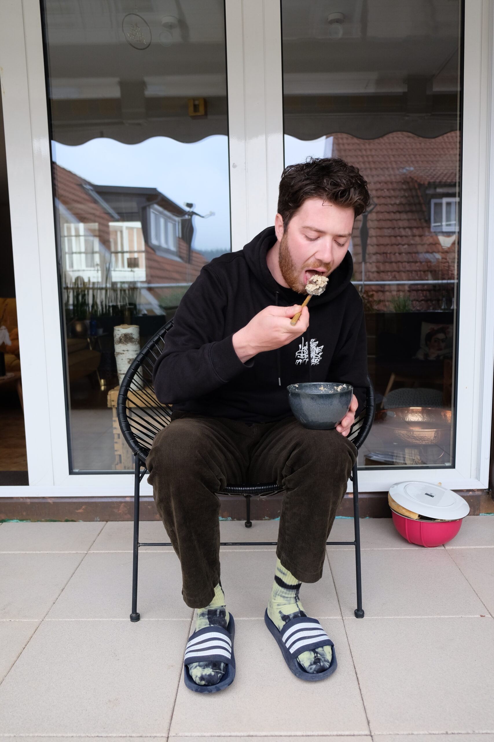 Junger Mann isst Porridge auf der Terrasse