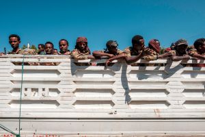 People sit in a white truck with their arms folded across it.