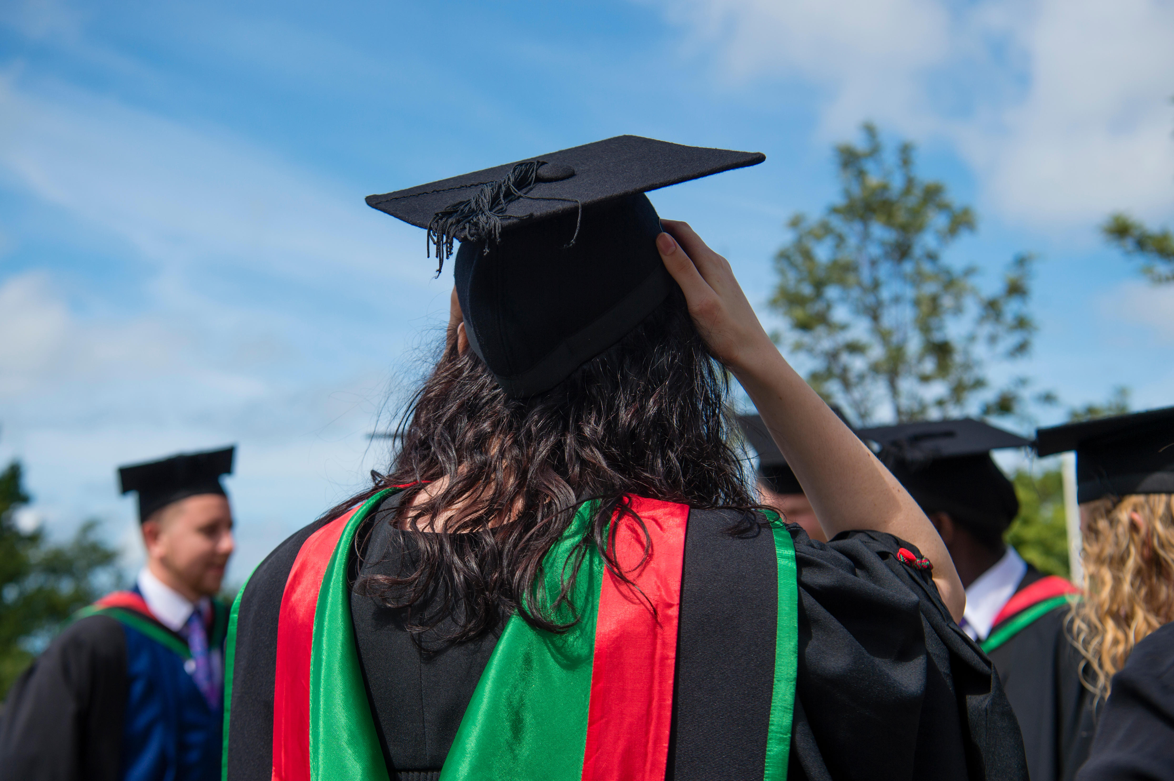 Rear back view of Aberystwyth university female students wearing traditional gowns, capes and mortar boards at their graduation day ceremony