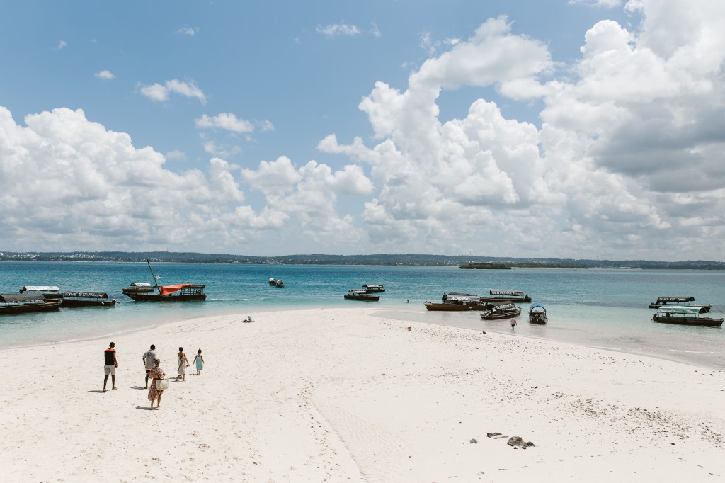 People walk on a beach in Zanzibar