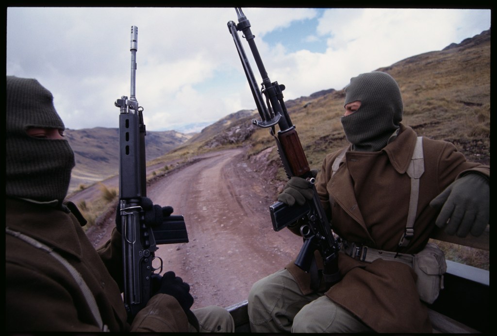 Armed soldiers ride in the back of a truck, which is part of a caravan delivering food and medical supplies to areas affected by attacks from the Shining Path terrorist group.