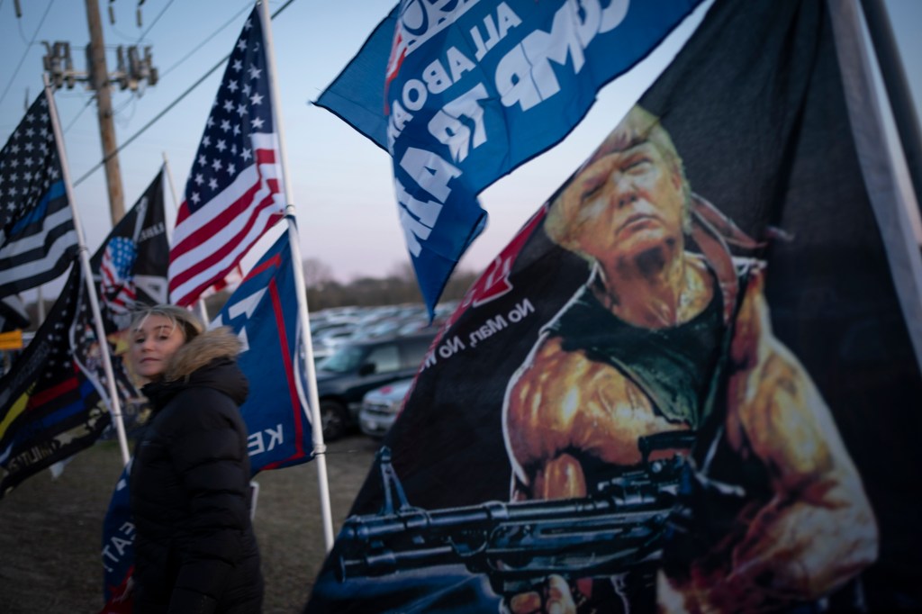 A Trump supporter walks past flags ahead of his rally, Monday, Nov. 2, 2020, in Kenosha, Wisconsin.