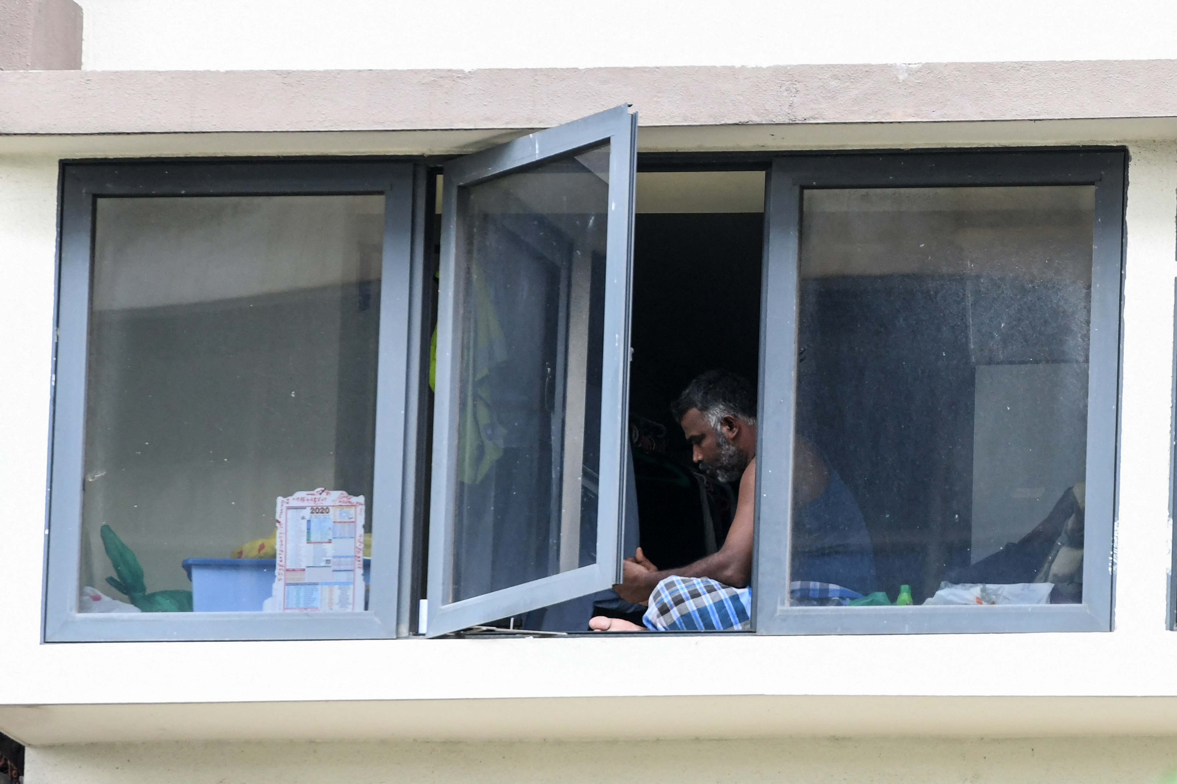 A migrant worker sits in a room at a foreign workers' dormitory. Photo: Roslan Rahman / AFP