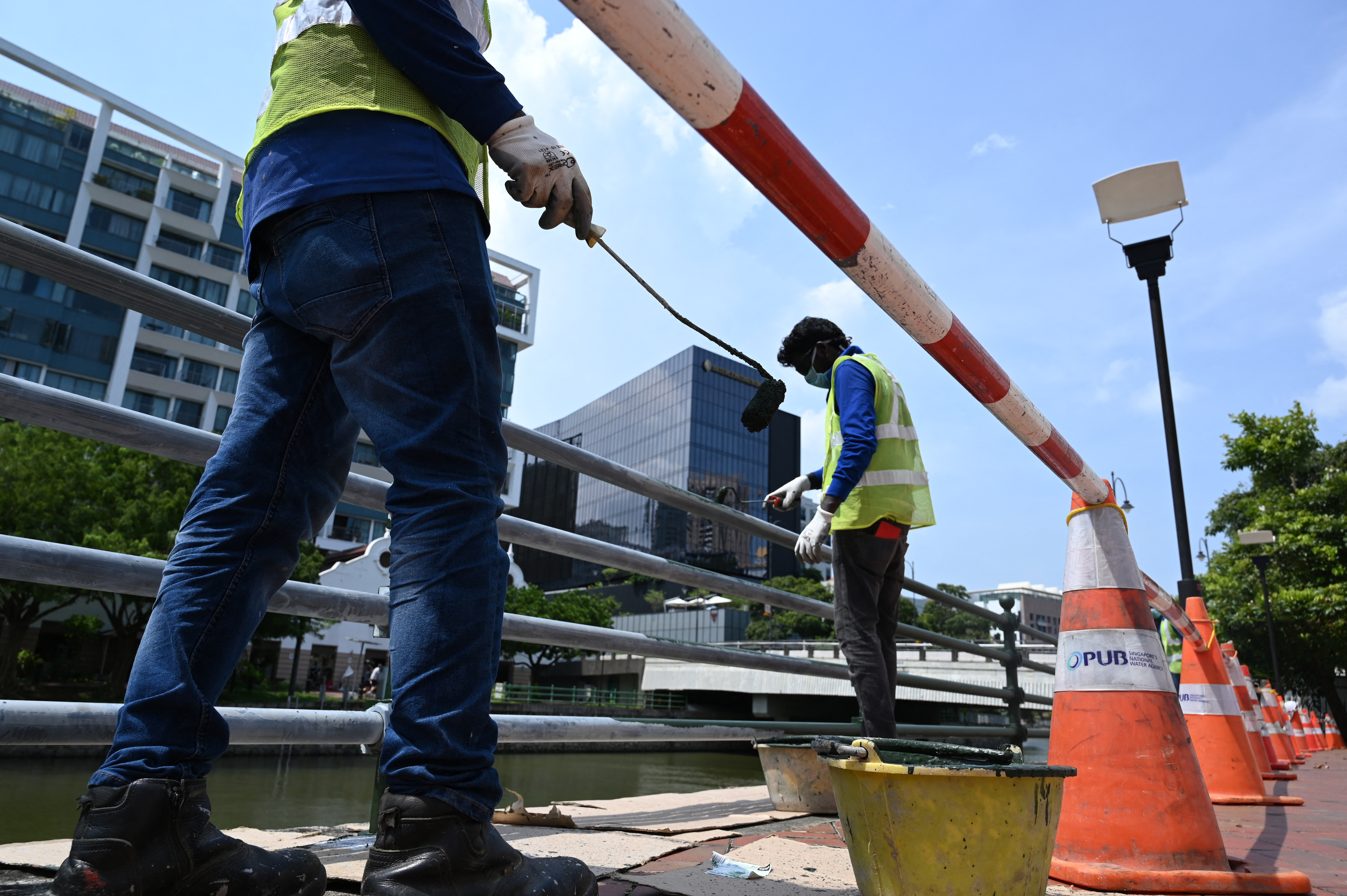 Workers paint a railing along the Singapore River. Photo: Roslan Rahman / AFP