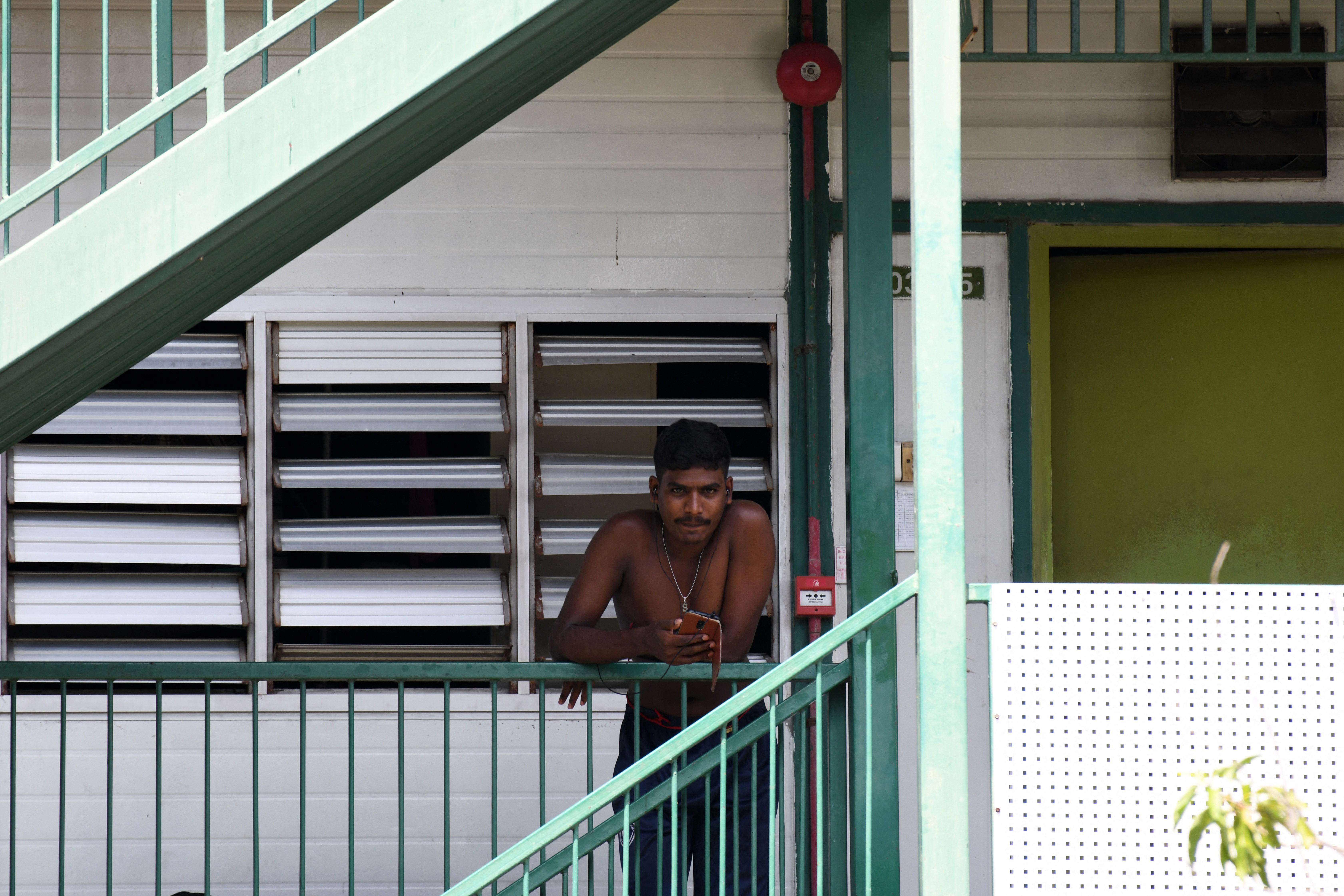 A man looks on from the balcony of a dormitory. Photo: Roslan Rahman / AFP