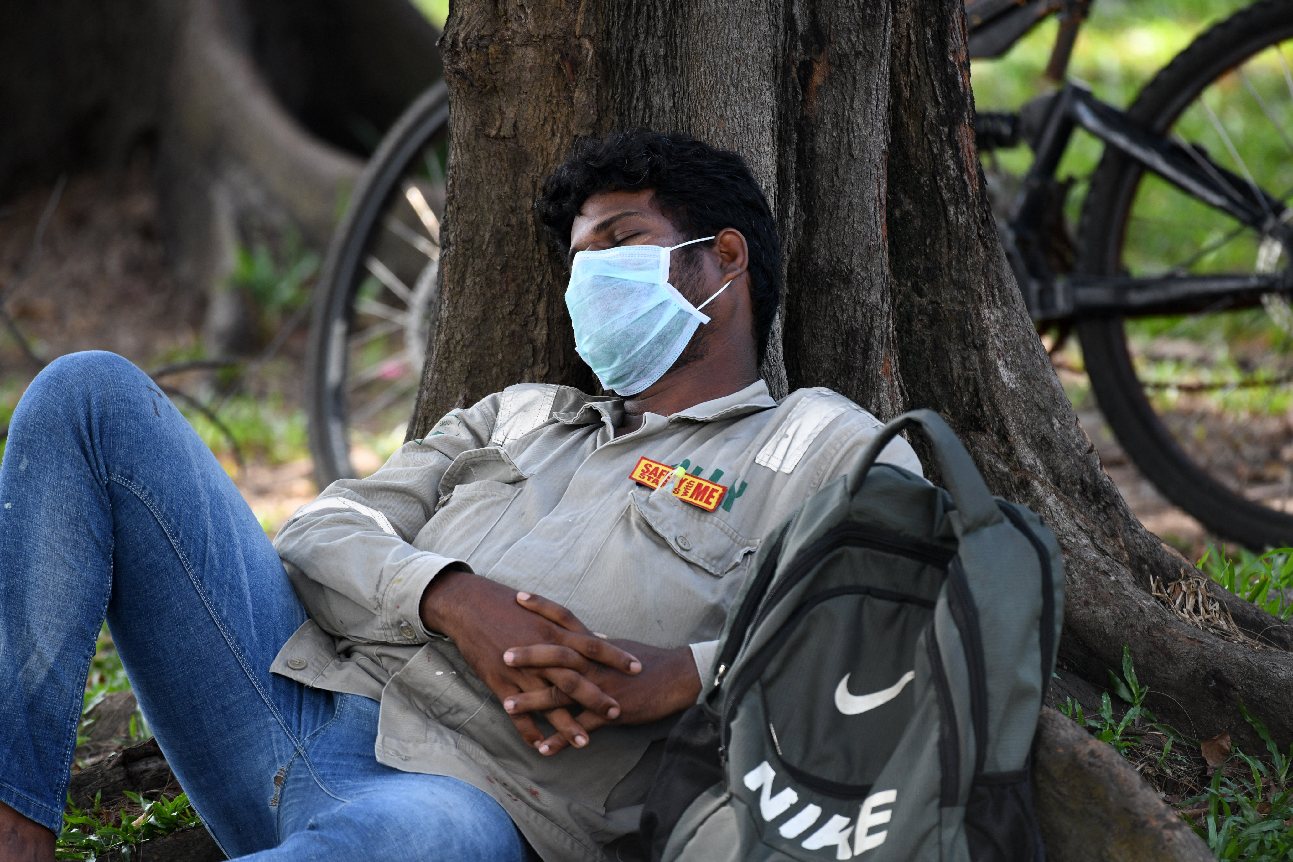 A worker takes a nap while waiting for transport. Photo: Photo: Roslan Rahman / AFP