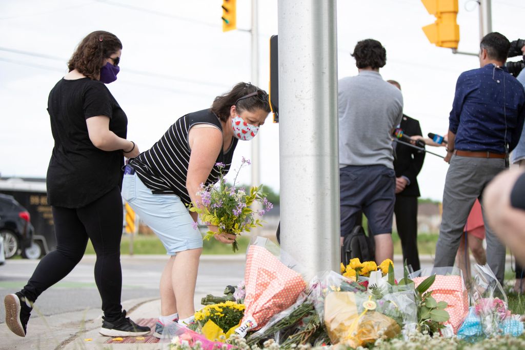 People pay their respects at the scene where a man driving a pickup truck struck and killed four members of a Muslim family in London, Ontario, on Monday