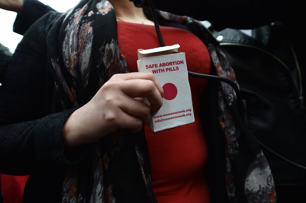 An unidentified woman displays an abortion pill packet after taking one of the pills as abortion rights campaign group ROSA, Reproductive Rights Against Oppression, Sexism and Austerity distribute abortion pills from a touring bus on May 31, 2018 in Belfa