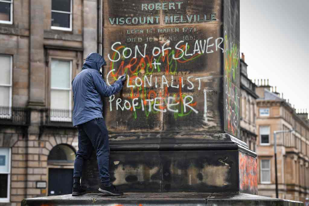 A member of the public attempts to clean graffiti from the Robert Dundas 2nd Viscount Melville statue in Edinburgh, Scotland. Photo: Jeff J Mitchell/Getty Images