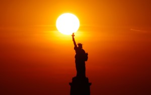 The sun sets behind the Statue of Liberty on June 5, 2021 in New York City. (Photo by Gary Hershorn/Getty Images)