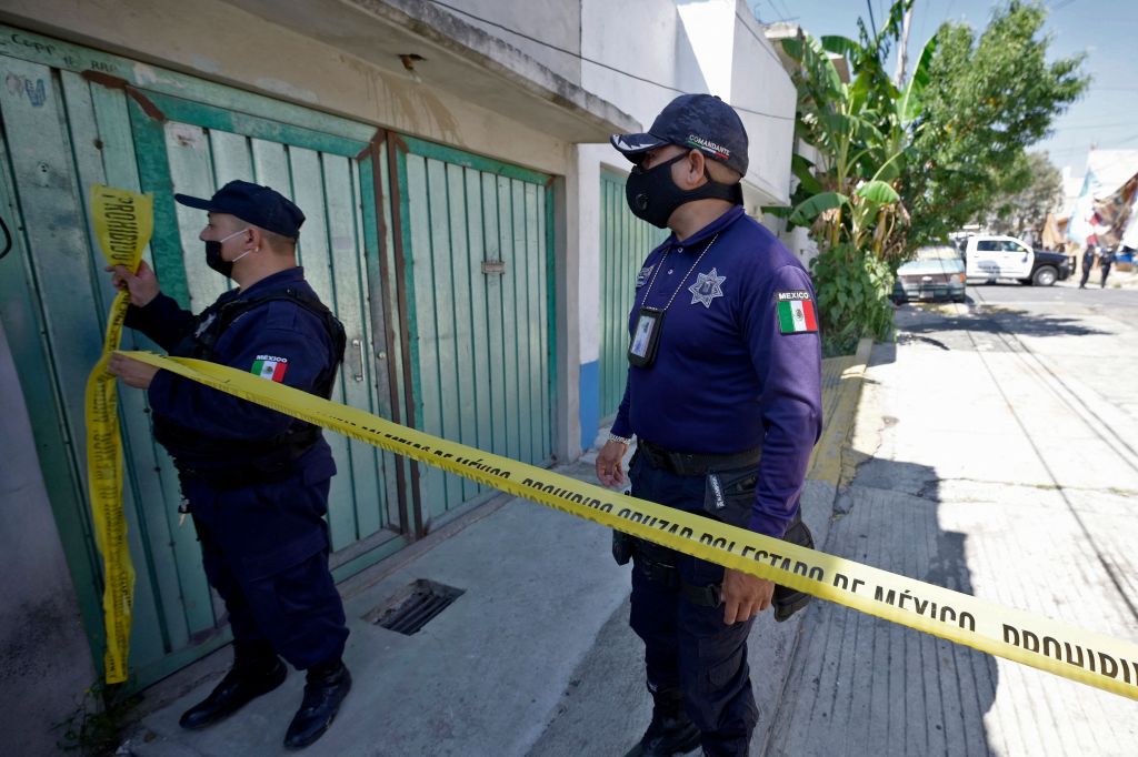 Dua anggota polisi memasang garis polisi di depan rumah