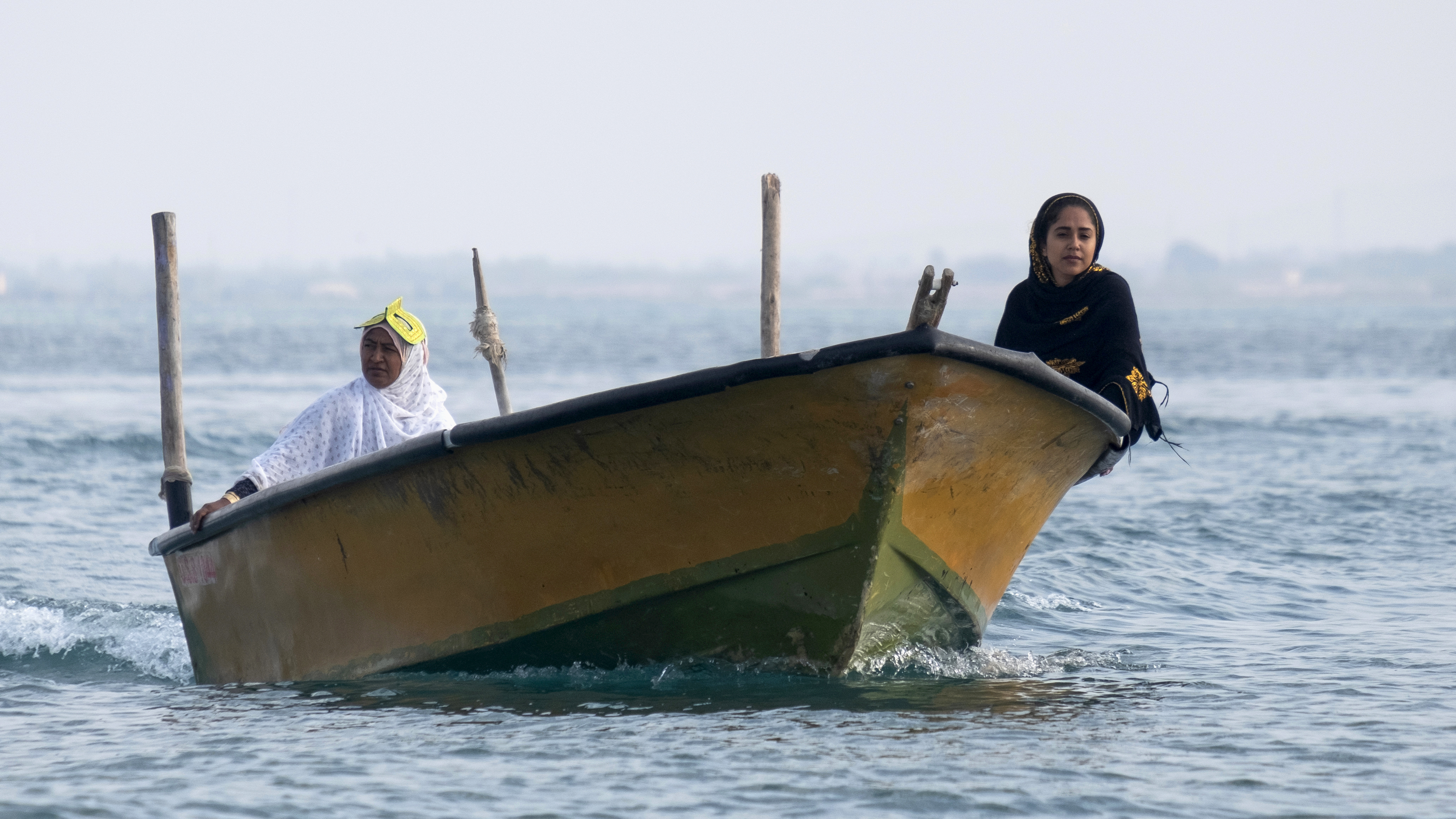 Dua perempuan mencari ikan dari atas kapal.