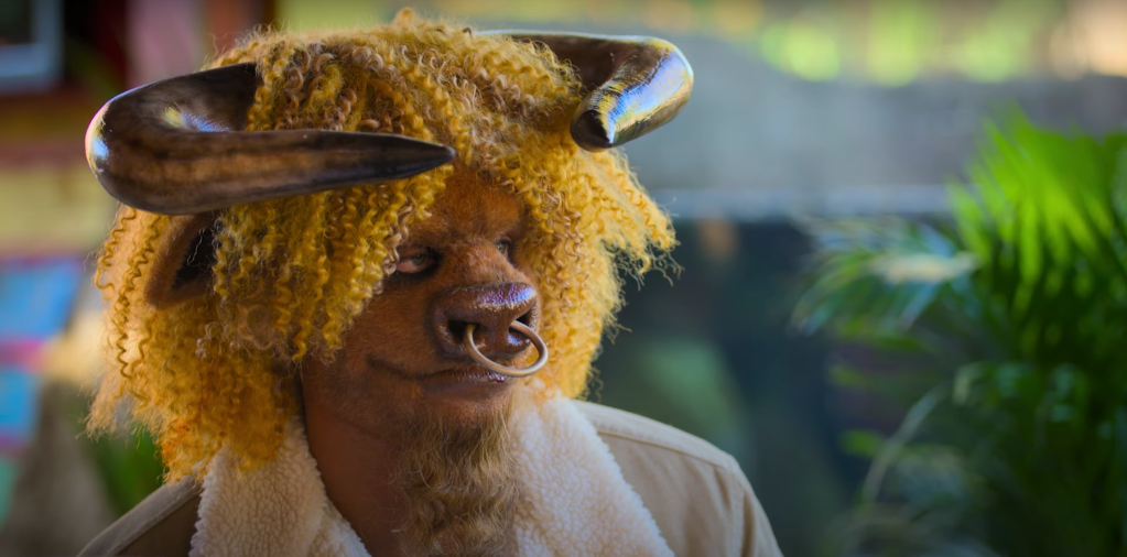 A screenshot from Sexy Beasts, showing a man dressed as a bull looking skeptically at the camnera.