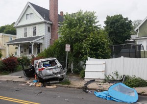 In this Saturday, June 26, 2021 photo, the wreckage of a car sits on a sidewalk after a stolen truck collided it and crashed into a building before a suspect fatally shot two people in Winthrop, Mass.