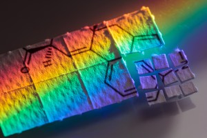 A rainbow refracted light beam shines on a strip of acid tabs.