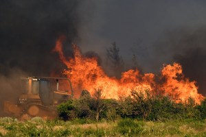 Una excavadora trabajando mientras la vegetación arde en llamas debido al incendio Lava en California