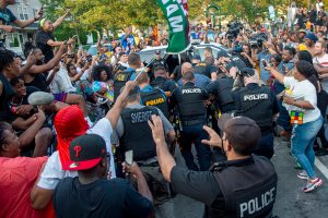 Police escort Edward Cagney Mathews through a crowd of people who had gathered outside his Mount Laurel, N.J., home, Monday, July 5, 2021.