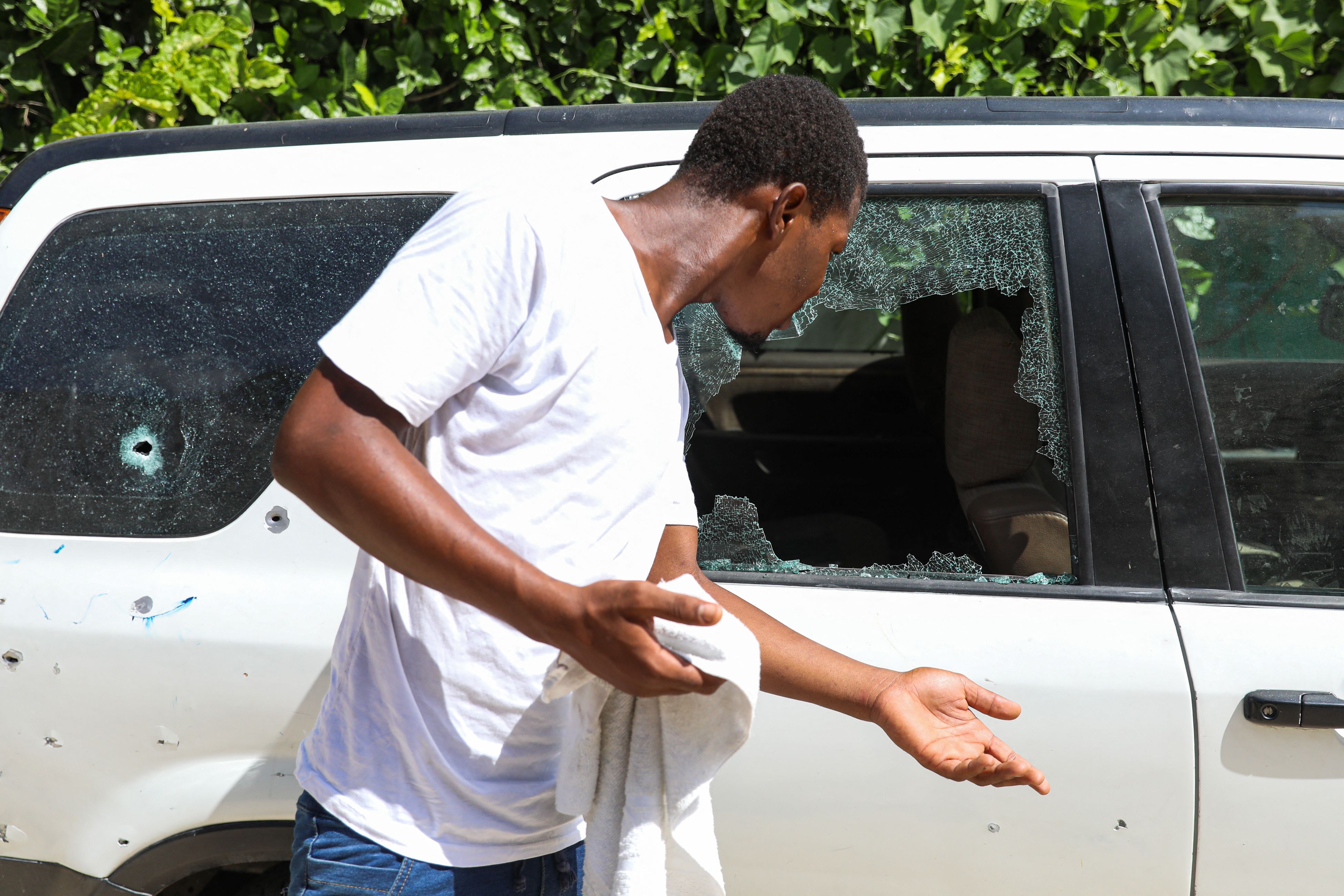 Un hombre mira los agujeros de bala en un automóvil fuera de la residencia del presidente. Foto: VALERIE BAERISWYL / AFP vía Getty Images